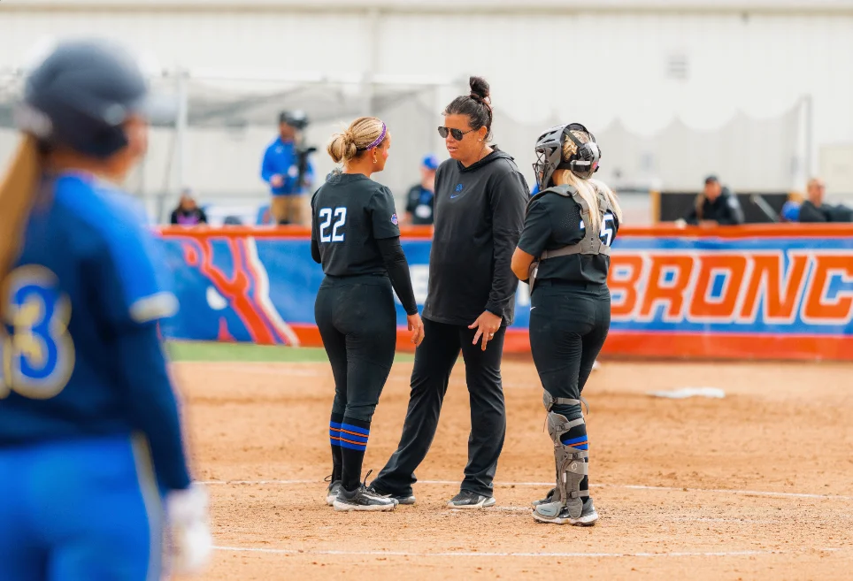 Allie Walljasper coaching a pitcher and catcher in the circle